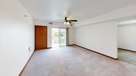 Located at 1434 Osauka Rd NE in Sauk Rapids, Minnesota, this single-floor unit offers a well-designed, functional layout with a warm, neutral color palette throughout. The open-concept living area is anchored by plush carpeting and a ceiling fan with integrated lighting, creating a comfortable and airy atmosphere. A half-wall partition separates the living space from the kitchen, which features warm-toned cabinetry, recessed lighting, light hardwood-style flooring, a double sink, and stainless steel appliances including a dishwasher, range, and refrigerator. The bedrooms are carpeted and generously sized, with one room featuring a sliding glass door that opens to a private balcony with exterior views. Additional bedrooms include sliding closets with built-in shelving for ample storage. The bathroom is clean and functional, equipped with a full soaking tub and shower combination finished in crisp white with chrome fixtures and tile flooring. A dedicated in-unit laundry room with hardwood-style flooring includes full-size washer and dryer units alongside wall-mounted shelving. Warm wood trim accents flow consistently throughout the unit, tying together the overall design with a cohesive, polished finish.