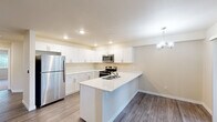 Located at 501 NE 112th Ave in Vancouver, WA, this well-appointed one-bedroom, one-bathroom residence offers a thoughtfully designed single-floor layout. The open-concept living area seamlessly connects the kitchen, dining room, and living room, creating an airy and functional shared space. The kitchen is a standout feature, showcasing crisp white shaker cabinetry, a peninsula with an integrated sink, stainless steel appliances including a refrigerator, range, microwave, and dishwasher, and recessed lighting accented by a stylish chandelier over the dining area. Durable wood-look flooring runs throughout the main living areas, adding warmth and continuity. The bedroom is a comfortable retreat, finished with plush carpet, a ceiling fan, and a window overlooking lush greenery, filling the room with natural light. Two closets provide ample storage. The full bathroom features a wide vanity with white cabinetry, a large mirror, and a shower-tub combination, all finished in a clean, neutral palette. A dedicated in-unit laundry room houses a full-size washer and dryer. A private balcony extends the living space outdoors. Warm beige tones and modern fixtures throughout lend the space a clean, move-in-ready ambiance.