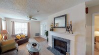 This single-story residence offers two bedrooms and two bathrooms within a thoughtfully arranged floor plan. The living room serves as the focal point of the home, featuring a stone-surround fireplace with a white mantle, ceiling fan, and French doors that invite natural light while providing access to the outdoors. Windows along the adjacent wall further brighten the carpeted space, which is generously sized for comfortable seating arrangements.

The dining area connects seamlessly to the living space and features hardwood-style flooring, a chandelier overhead, and a closet housing the in-unit washer and dryer. The galley-style kitchen is equipped with ample white cabinetry, a dishwasher, range, and refrigerator, all set above hardwood-style flooring.

Both bedrooms are carpeted and include ceiling fans, natural light from windows, and closet space. The rooms offer comfortable proportions suitable for full bedroom furnishings. Each bathroom includes a full tub-shower combination. Textured ceilings are consistent throughout the home, contributing to its classic character. The overall layout, as seen in the 3D overview, is efficient and well-connected, making practical use of the available space.