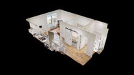 Located at 201 8th Avenue Northwest in Austin, MN, this efficiently designed 1-bedroom, 1-bathroom apartment spans 410 square feet across a single floor. The combined kitchen and living area is anchored by light hardwood flooring and a large window that fills the space with natural light while offering outdoor views of the surrounding area. The kitchen features a two-tone cabinet design with dark lower and white upper cabinetry, light countertops, and a full suite of stainless steel GE appliances including a refrigerator, electric range, over-the-range microwave, and dishwasher. The living area comfortably accommodates a seating arrangement, with a wall-mounted HVAC unit providing climate control. A sliding barn door leads to the 80 sq ft bedroom, which offers a cozy, carpet-floored retreat with clean white walls. The bathroom is finished with light hardwood-style flooring, a walk-in shower with matte black fixtures, a dark vanity with an undermount sink, and a framed mirror. The unit's clean, contemporary aesthetic and functional layout make it a practical and attractive living space.
