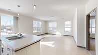 Located on Dr. Martin Luther King Jr. Drive in Milwaukee, WI, this well-designed two-bedroom, two-bathroom unit offers a thoughtful single-level layout with a clean, contemporary aesthetic throughout. The open-concept kitchen and living area serves as the heart of the unit, featuring a central island with a light stone countertop and integrated sink, crisp white cabinetry extending to the ceiling, and a full suite of stainless steel appliances including a refrigerator, range, and microwave. Pendant lighting accents the island, while recessed lighting and large windows fill the space with natural light. A sliding glass door provides access to a private balcony. Light wood-style flooring extends through the main living areas, complementing the neutral, bright color palette. The spacious primary bedroom is generously sized, bathed in natural light, and features plush carpeting. The second bedroom also offers carpet flooring and multiple windows with exterior views. Both bathrooms are finished with white vanity cabinetry, mirrors, and light wood-tone sliding doors. A dedicated closet provides additional storage. The hallways connect each room seamlessly, with warm wood-framed interior doors adding subtle contrast to the crisp white walls throughout.