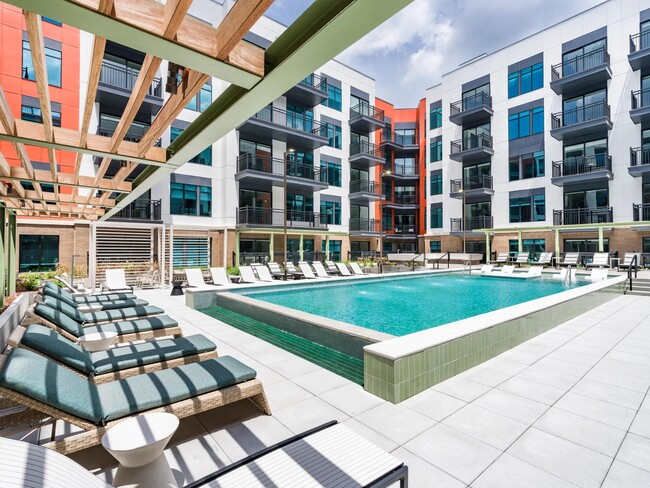 Resort-style pool with in-water loungers, shaded seating, and a spacious sundeck for warm-weather relaxing. - Modera SoBro