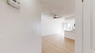 Located at 150 S Roosevelt Rd in Mesa, Arizona, this efficiently laid-out single-floor unit offers a thoughtful arrangement of living spaces designed to maximize comfort and functionality. The open living area features light wood-look vinyl flooring that runs throughout, clean white walls, and a textured ceiling with a ceiling fan that promotes airflow — a practical touch well-suited to the Arizona climate. Natural light filters in through a large window dressed with vertical blinds, brightening the space considerably.

The kitchen is a standout feature, outfitted with white cabinetry, crisp white quartz-style countertops, and a classic white subway tile backsplash. Stainless steel appliances — including a range, over-the-range microwave, and refrigerator — lend a modern, clean aesthetic to the galley-style layout. The kitchen flows seamlessly into the living area, creating a cohesive and open feel.

The bathroom is finished in all-white with a full soaking tub and shower combination, complemented by a towel bar and straightforward, clean fixtures. A dedicated closet provides essential storage. Throughout the unit, the consistent use of light tones, wood-look flooring, and ceiling fans creates a bright, airy ambiance that feels welcoming and easy to maintain.