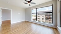 Located at 2307 N Tryon St in Charlotte, NC, this 1,000-square-foot apartment offers two bedrooms and two bathrooms across a single floor. The unit features a combined kitchen and living area, two bedrooms, two bathrooms, and two closets, providing a practical and well-organized layout.

The interior is finished with light hardwood-style flooring that runs throughout, contributing to a bright and cohesive aesthetic. Neutral-toned walls complement the clean, modern design. The primary bedroom measures 160 square feet and is equipped with a ceiling fan and a large floor-to-ceiling window that frames views of the surrounding urban neighborhood, allowing for generous natural light. The oversized window features a dark metal frame, adding a contemporary industrial detail to the space.

The unit's layout supports comfortable everyday living, with dedicated closet storage in both bedrooms. The combined kitchen and living area provides an open, flexible space for dining and relaxation. The building's exterior and surrounding streetscape, visible from the upper-floor windows, reflect the vibrant character of Charlotte's North Tryon corridor.
