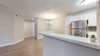 Located at Huntington Place Drive in Sarasota, Florida, this single-story residence offers a thoughtfully designed open-concept layout that seamlessly connects the main living areas. Wood-look flooring runs throughout, lending a warm, cohesive feel to every room, while neutral gray walls and textured ceilings create a clean, contemporary backdrop.

The kitchen is a standout feature, outfitted with crisp white shaker cabinetry, granite-look countertops, a gray subway tile backsplash, and a full suite of stainless steel appliances. A peninsula counter provides a natural division between the kitchen and the adjoining dining area, which is accented by an elegant chandelier. The open living room benefits from a ceiling fan and flows easily into surrounding spaces.

The bedrooms are comfortably sized, each equipped with a ceiling fan, natural light from window blinds, and built-in closets with organized shelving. Two bathrooms serve the home: one features a white vanity with stone-look countertop and a shower-tub combination, while the second offers similar finishes with a curtained tub surround. The overall ambiance is fresh, functional, and move-in ready.