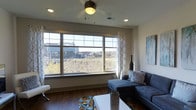 This 2-bedroom, 2.5-bathroom single-floor residence offers a well-designed layout that balances comfort and functionality. The living area serves as the heart of the home, anchored by a large multi-pane picture window that floods the space with natural light and frames sweeping views of the surrounding cityscape and natural landscape beyond. Rich hardwood flooring runs throughout, complementing the neutral wall tones and modern aesthetic. A ceiling fan with integrated lighting adds both style and practicality to the living room. Recessed lighting provides consistent, ambient illumination throughout the space. The open feel of the main living area makes it ideal for both relaxing and entertaining. Tasteful design details, including clean architectural lines and well-proportioned rooms, contribute to the overall sense of openness. With two full bedrooms and two and a half bathrooms, the layout accommodates a variety of living arrangements. The combination of ample natural light, city and greenery views, and thoughtfully designed interiors makes this a bright, inviting, and highly functional residence.