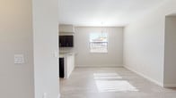 This well-maintained single-floor residence offers a bright, modern interior defined by a neutral color palette and clean finishes throughout. The open-concept kitchen is a standout feature, outfitted with dark espresso cabinetry, light granite countertops, and a full suite of stainless steel appliances including a range, microwave, and dishwasher. A window above the sink allows natural light to fill the space. The kitchen flows seamlessly into the dining area, which features light wood-style flooring, a pendant light fixture, and a window with blinds that invites additional natural light. The layout, as seen in the dollhouse view, connects the main living areas efficiently while providing distinct bedroom spaces. The bedrooms are finished with plush neutral carpeting and feature windows that bring in natural light, creating a comfortable and restful atmosphere. The bathroom is equipped with a dark-cabinetry vanity, a wide mirror, white countertop, and a tiled shower area with a contrasting dark tile surround. Clean white walls, light-toned flooring in the wet areas, and consistent trim work throughout contribute to a cohesive and polished aesthetic across the entire space.