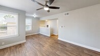Located at 1 Nevada Avenue in Tacoma, WA, this single-floor, 2-bedroom, 1-bathroom unit offers a functional and comfortable layout designed for everyday living. The combined kitchen and living room area anchors the home, with the living space featuring wood-look hardwood-style flooring, neutral gray walls, and a ceiling fan with light. Large windows invite natural light and outdoor views of the surrounding neighborhood. A half-wall partition connects the living area to the kitchen, which is equipped with white cabinetry, dark granite-style countertops, a white electric range, a full-size refrigerator, and durable wood-look flooring. A natural light-filled window above the counter adds brightness to the cooking space. Both bedrooms are carpeted in warm beige tones and feature ceiling fans with lights and windows overlooking greenery and neighboring properties. The primary bedroom includes attic access. The full bathroom is clean and bright, finished in white tile with a shower-tub combination, a dark countertop vanity, and a frosted privacy window. A dedicated utility room and hallway complete the layout. The unit's cohesive neutral palette and practical design create a welcoming, move-in-ready atmosphere.