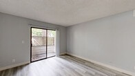 This well-appointed 1-bedroom, 2-bathroom unit is located at 6736-6756 N Clybourn Ave in Los Angeles, CA. The single-floor layout makes efficient use of its space, featuring light gray walls, wood-look luxury vinyl flooring, and textured ceilings throughout, creating a cohesive and modern aesthetic.

The combined living and dining area is bright and open, highlighted by a sliding glass door that leads to a private patio with latticed privacy fencing and views of mature surrounding trees. The galley-style kitchen is thoughtfully designed with white shaker cabinetry, white quartz countertops, a black matte sink faucet, and stainless steel appliances including a gas range and a retro-style refrigerator.

The bedroom is a comfortable size, offering a sliding-door closet, a window with natural light and outdoor views, and the same consistent flooring found throughout the unit. Four total closets provide ample storage across the space.

Both bathrooms are updated and clean. One features a white vanity with a modern oval mirror and a separate tub/shower combination adorned with marble-style tile surround. The unit's neutral palette and updated finishes make it a versatile, move-in-ready space in the North Hollywood neighborhood of Los Angeles.