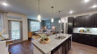 Located in Houston, TX, this well-appointed one-bedroom, one-bathroom unit offers a thoughtfully designed single-floor layout that balances comfort and style. The kitchen serves as a focal point of the living area, showcasing dark espresso cabinetry, stainless steel appliances, a subway tile backsplash, and a spacious granite-topped island with a built-in sink and pendant lighting overhead. Hardwood-style flooring flows throughout the main living areas, complementing the warm, contemporary aesthetic. The open-concept design connects the kitchen seamlessly to a dedicated dining nook, framed by sage-green accent walls and a large window that fills the space with natural light. The living room continues this inviting palette, featuring the same teal-toned walls, a ceiling fan, and generous window views of the surrounding greenery. The bedroom is a tranquil retreat with plush carpeting, a ceiling fan, and a large window. The full bathroom includes a granite vanity, dark cabinetry consistent with the kitchen, wood-style flooring, and a full soaking tub with shower. A walk-in closet is accessible directly from the bathroom, offering practical storage. Recessed lighting and carefully placed pendant fixtures provide a polished finish throughout the unit.