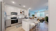 Located in New Port Richey, FL, this thoughtfully designed one-bedroom, one-bathroom residence offers a comfortable and modern living experience across a single floor. The open-concept layout seamlessly connects the kitchen, dining, and living areas, maximizing the sense of space throughout.

The kitchen is a standout feature, showcasing two-tone cabinetry in white and light gray, a granite-topped island with bar seating, stainless steel appliances including a refrigerator, range, and microwave, a subway tile backsplash, and open shelving for added functionality and style.

The living room is bright and inviting, benefiting from large windows that invite natural light. A ceiling fan adds comfort, while light wood-style flooring runs throughout the main living areas, creating a cohesive and airy feel.

The bedroom is a serene retreat, featuring a soft blue accent wall, generous natural light from a large window, and direct access to the bathroom. The bathroom is clean and well-appointed, offering a combined tub and shower with tile surround, a vanity with granite countertop, and the same light wood-style flooring for a consistent aesthetic. A dedicated closet completes the unit's practical layout.