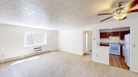 This single-floor residence features 2 bedrooms and 3 bathrooms across a thoughtfully arranged floor plan. The living room serves as the central gathering space, featuring wall-to-wall carpeting, a textured ceiling, and a large window that invites natural light and outdoor views. A ceiling fan adds functional comfort, while a baseboard heating system and wall-mounted air conditioning unit ensure year-round climate control.

The kitchen is efficiently laid out with rich, dark wood cabinetry, granite-style countertops, hardwood flooring, and white appliances including a range and refrigerator. A pass-through window connects the kitchen to the living area, enhancing the open feel between spaces.

The generously sized primary bedroom includes a closet and direct access to a private bathroom, while the second bedroom offers comfortable proportions with carpeting, a wall-mounted AC unit, and baseboard heating. Both rooms feature neutral tones and ample wall space.

The bathrooms are clean and functional, featuring white vanities with mirrored medicine cabinets and tiled tub-and-shower combinations equipped with handheld showerheads and safety grab bars. A hallway connects the rooms cohesively. Overall, the space presents a bright, neutral palette with practical amenities throughout.