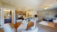 This single-story, one-bedroom, one-bathroom unit offers a thoughtfully designed layout that maximizes both functionality and comfort. The open-concept kitchen and living area serves as the heart of the home, featuring rich dark-toned cabinetry, stainless steel appliances, white quartz countertops, and a bold navy blue kitchen island with seating for multiple bar stools, illuminated by stylish pendant lighting. The kitchen flows seamlessly into the dining and living areas, where light hardwood-style flooring, neutral warm-toned walls, and a ceiling fan create an inviting atmosphere. The living room benefits from multiple windows that bring in natural light and outdoor views. The bedroom is a calm retreat with its own window, ceiling fan, and direct access to the rest of the unit. The full bathroom features a blue-toned vanity with modern hardware, a large mirror with overhead lighting, and a shower-tub combination. A dedicated laundry room with a full-sized washer and dryer adds everyday convenience. A closet provides additional storage. Consistent light hardwood-style flooring and neutral finishes tie the entire space together for a cohesive, modern aesthetic.