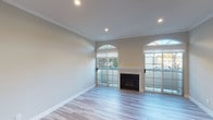 Located at 5447 White Oak in the Encino neighborhood of Los Angeles, this single-floor residence offers a well-designed layout with a neutral color palette and quality finishes throughout. The living area is a standout space, anchored by a classic fireplace and framed by elegant arched windows that allow natural light to pour in. Sliding glass doors with grid detailing open to an outdoor area, enhancing the sense of openness. Light-toned hardwood-style flooring flows through the main living areas, complemented by crisp crown molding and recessed lighting overhead. The kitchen is thoughtfully appointed with dark gray cabinetry, sleek white countertops, a modern subway tile backsplash, and stainless steel appliances including a gas range and built-in microwave. The bedroom features plush carpeting, an arched window, a ceiling fan, and a generous walk-in closet with dual hanging rods. The bathroom is clean and functional, offering a combined tub and shower enclosed by sliding glass doors, a vanity with matching gray cabinetry, and light wood-style flooring. A stepped entryway with hardwood-style flooring provides a welcoming transition into the home. Overall, the space presents a cohesive, modern aesthetic suited for comfortable living.