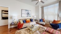 This thoughtfully designed single-floor residence offers a cohesive blend of modern finishes and comfortable living spaces. The open-concept kitchen is a standout feature, outfitted with rich dark wood cabinetry, granite countertops, a white waterfall-edge island with bar seating, stainless steel appliances, a built-in wine cooler, and elegant pendant lighting — making it equally suited for everyday cooking and entertaining. Hardwood flooring flows throughout the main living areas, anchoring a bright and airy living room that benefits from large windows, a ceiling fan, and generous natural light. The living area provides ample space for multiple seating arrangements. The primary bedroom is a serene retreat with a ceiling fan, walk-in closet, and en suite bathroom featuring a glass-enclosed walk-in shower, granite vanity countertop, and marble-style tile. The second bedroom is equally well-appointed with natural light and soft neutral tones. A second full bathroom includes a soaking tub with marble-style tile surround. Throughout the residence, clean white walls, tasteful fixtures, and quality materials come together to create a refined yet livable atmosphere.