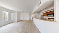 Located at 3644 S Fort Apache Rd in Las Vegas, NV, this two-story, one-bedroom, one-bathroom unit offers a well-organized layout spread across two levels. The ground floor houses an attached garage with automatic door opener and concrete flooring, providing convenient and secure parking. A carpeted staircase with a clean white handrail leads to the main living level above.

The upper floor features an open-concept living room, dining area, and kitchen. The living room is generously sized with soft carpeting, track lighting, and large windows that allow abundant natural light to fill the space. The kitchen is equipped with warm wood cabinetry, granite-style countertops, a breakfast bar peninsula, and standard appliances including a refrigerator, range, and built-in microwave. A balcony extends off the main living area, offering an outdoor retreat.

The bedroom features high ceilings, a ceiling fan, plush carpeting, and multiple windows that bring in natural light. It is accompanied by a spacious walk-in closet with built-in wire shelving on three walls, offering ample storage. The full bathroom includes a tub-shower combination with tiled surround, a granite-topped vanity, hardwood flooring, and a large mirror. A hallway connects the bedroom and bathroom, completing the functional upper-level floor plan.