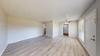 This single-floor, 2-bedroom, 1-bathroom residence offers a functional and efficiently designed layout with a cohesive, modern aesthetic throughout. Light-toned luxury vinyl plank flooring runs throughout the unit, complementing the neutral gray-and-white color palette that creates a bright, clean atmosphere.

The spacious living room serves as the central gathering area, featuring a textured ceiling, a ceiling fan with light fixture, and a large front-facing window that invites ample natural light and outdoor views. The kitchen is accessible directly from the living area and is equipped with white cabinetry, granite-style countertops, a double stainless steel sink, and matching appliances, offering a practical and tidy workspace.

A connecting hallway leads to the two bedrooms, each outfitted with ceiling fans, windows with blinds, and generous wall space. The primary bedroom provides a comfortable footprint with its own dedicated closet. The second bedroom mirrors the same clean finishes and benefits from natural light. Two closets throughout the unit offer practical storage solutions.

The bathroom features a full tub-shower combination with white tile surround and chrome fixtures, maintaining the unit's consistent, crisp aesthetic. The hallway ties all rooms together in a straightforward, easy-to-navigate layout ideal for everyday living.