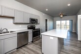 Located at 3821 Eastbrook St in Iowa City, Iowa, this well-appointed 2-bedroom, 2-bathroom residence offers a thoughtfully designed single-level layout. Light-toned luxury vinyl plank flooring flows throughout, lending a clean and cohesive aesthetic to every room.

The open-concept kitchen is a standout feature, equipped with stainless steel appliances including a range, microwave, dishwasher, and refrigerator. Gray shaker-style cabinetry pairs with light countertops and a central island that provides additional prep space and storage. A built-in pantry with shelving adds generous storage capacity.

The kitchen flows seamlessly into the living room, which is bathed in natural light from large sliding glass doors opening onto a private balcony with outdoor views. A ceiling fan completes the comfortable, airy feel of the living area.

The spacious primary bedroom includes its own ceiling fan and connects to a walk-in closet outfitted with wire shelving. The second bedroom is well-proportioned with a window and ceiling fan. Both bathrooms feature gray vanity cabinetry with white countertops and wood-look flooring. The layout also includes two closets total, ensuring ample storage throughout this efficient and modern residence.