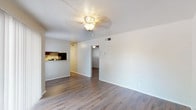 This single-floor unit offers a clean, modern aesthetic highlighted by durable hardwood-style flooring that runs consistently throughout the space. The open living area is bright and welcoming, featuring a ceiling fan with a light fixture and a sliding glass door fitted with vertical blinds that allows natural light to fill the room while providing access to an outdoor patio area. A pass-through connects the living area to the kitchen, which is thoughtfully designed with dark espresso cabinetry, granite-style countertops, a stainless steel double-basin sink, and a dishwasher — offering both functionality and style. Each bedroom is comfortably proportioned with its own ceiling fan, neutral-toned walls, and the same hardwood-style flooring, creating a cohesive feel across the unit. The bathroom features a dark-framed vanity mirror, a wide granite-topped countertop with ample storage below, and a full bathtub with white tile surround. A dark upper cabinet above the toilet provides additional storage. Throughout the unit, clean white walls, consistent trim, and updated finishes contribute to a fresh and well-maintained atmosphere.