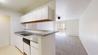 Located at 115 W Limberlost Dr in Tucson, Arizona, this single-floor, 2-bedroom, 2-bathroom residence offers a practical and well-organized layout. The galley-style kitchen features white cabinetry extending to the ceiling for ample storage, gray laminate countertops, a stainless steel sink, a dishwasher, and a full-size refrigerator, all finished with light tile flooring. A peninsula counter opens directly to the living room, creating a connected and functional flow. The living room is carpeted, enhanced by a ceiling fan with light fixture, and features a sliding glass door with vertical blinds that invites natural light and outdoor access. Both bedrooms are carpeted and include ceiling fans, with the primary bedroom offering a mirrored closet and a dedicated en-suite bathroom. The second bedroom provides a spacious sliding-door closet. The bathrooms include white vanity cabinetry with gray countertops; one features a full tub-shower combo with white tile surround. A dedicated in-unit laundry area accommodates a full-size washer and dryer side by side on tile flooring. A hallway connects the living spaces to the bedrooms and bathrooms, completing this efficiently designed Tucson residence.