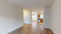This two-floor residence offers a well-organized layout with a variety of functional spaces across its levels. The main floor features a bright, open living area finished with smooth hardwood-style flooring that extends throughout. A sliding glass door with vertical blinds floods the living room with natural light and provides access to the outdoors. The kitchen is efficiently designed in an L-shaped configuration, outfitted with warm wood cabinetry, granite-style countertops, stainless steel appliances including a gas range, microwave, and dishwasher, and tile flooring. A hallway on the main floor provides access to a pair of six-panel closet doors, offering generous storage. The bathroom features tile flooring, a wood vanity with a white countertop, a wall mirror with vanity lighting, and a window for natural ventilation. The upper level hosts carpeted bedrooms, each offering a calm, neutral palette and ample natural light through large windows. The lower level includes a generously sized finished recreation room with carpet and small windows near the ceiling, as well as a separate unfinished utility and storage area with concrete walls and exposed structural framing, ideal for mechanical systems and additional storage.