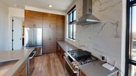 Located on W Worthington Ave in Charlotte's vibrant South End neighborhood (28203), this contemporary high-rise residence delivers a refined urban living experience through thoughtful design and premium finishes throughout. Light wood-tone flooring flows seamlessly across the open layout, complemented by crisp white walls and recessed lighting.

The chef's kitchen is a true centerpiece, showcasing rich wood cabinetry, a professional-grade stainless steel range, a stainless steel refrigerator, and a dramatic floor-to-ceiling marble slab backsplash. A stainless steel range hood anchors the cooking area, while large black-framed windows frame expansive views of the Charlotte skyline and surrounding cityscape.

The generously sized bedrooms each feature large black-framed windows that flood the rooms with natural light and offer sweeping elevated views of the city. Ceiling fans provide added comfort throughout.

The primary bathroom is a spa-inspired retreat, featuring a freestanding soaking tub enclosed within a floor-to-ceiling white subway tile surround, dark mosaic tile flooring, and sleek matte black fixtures. A wide vanity with a wood base and white countertop lines the hallway leading to the wet room. A secondary full bathroom mirrors the same high-end aesthetic with warm wood cabinetry and white countertops.