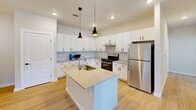 Located at 2700 Emerald Green Way in Knoxville, TN, this well-designed 2-bedroom, 2-bathroom single-floor home offers a clean, modern aesthetic throughout. The open-concept kitchen and living area serves as the heart of the home, anchored by a central island with a sink and light countertops, white shaker-style cabinetry with matte black hardware, a tile backsplash, stainless steel appliances, and stylish pendant lighting. Light wood-look flooring flows throughout the main living areas, enhancing the bright, airy feel. A dedicated pantry provides generous additional storage with wrap-around cabinetry and ample counter space. The living area is complemented by a ceiling fan and a door leading directly to the private patio, with windows inviting natural light and outdoor views. Both bedrooms feature plush carpet, closets, and windows overlooking the surroundings — the primary bedroom includes a walk-in closet. Each bathroom is finished with white cabinetry, neutral countertops, and matte black hardware; one bathroom features a tub/shower combo, while the other includes accessibility-friendly grab bars. A hallway connects the bedrooms, bathrooms, and a convenient in-unit laundry area, rounding out this functional and attractive home.