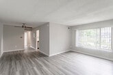 This single-floor residence offers a thoughtfully designed layout that balances comfort and functionality. The open living and dining area is finished with durable wood-look flooring and neutral gray walls, creating a bright, versatile space. A large window with vertical blinds invites natural light and provides outdoor views, while a textured ceiling adds subtle architectural character.

The kitchen is a standout feature, showcasing white shaker-style cabinetry, granite-look countertops, a classic white subway tile backsplash, and a full suite of stainless steel appliances including a gas range, microwave, dishwasher, and refrigerator. Wood-look flooring continues seamlessly through this space.

Multiple bedrooms are finished with plush carpeting and painted in soft, neutral tones. Each room benefits from windows that frame views of surrounding greenery, and several include closets for ample storage. The rooms offer a comfortable, quiet atmosphere well-suited for rest or a home office.

The bathroom is clean and contemporary, featuring white tile wainscoting, a modern floating vanity with an integrated sink, a large mirror, and a window that provides natural ventilation and light. The tiled flooring completes the polished look. Throughout the residence, consistent design choices lend a cohesive, move-in-ready feel.