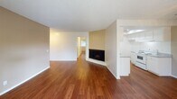 Located at 1950–2010 E Santa Clara Ave in Santa Ana, CA, this single-floor unit offers a well-organized layout with a blend of practical finishes throughout. The open living area is a standout feature, showcasing rich hardwood-style flooring that extends across the main living and dining spaces. A wood-paneled accent wall frames a sleek, black-trimmed fireplace, adding a classic focal point to the room. A ceiling fan overhead provides comfortable air circulation, and the open sight lines give the space a generous, airy feel.

The kitchen is efficiently designed with white cabinetry, granite-style laminate countertops, and a white electric range, offering ample storage through both upper and lower cabinets. The warm wood-look flooring continues seamlessly into this space.

The bedrooms are carpeted for comfort and feature textured ceilings and ceiling fans for climate control. Each bedroom includes closet space with built-in shelving and hanging rods, providing practical storage solutions.

The bathrooms are finished in a clean, neutral palette. One bathroom features a vanity with a large mirror, globe lighting, and granite-style countertops, while another includes a full shower-tub combination. Wood-look flooring ties the bathrooms cohesively to the rest of the unit. Overall, the space presents a functional and straightforward living environment in a convenient Santa Ana location.