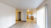 Located at 1605 SE Maple St in Hillsboro, Oregon, this 2-bedroom, 1-bathroom single-floor unit offers a functional and straightforward layout. The open living and kitchen area is anchored by light wood-style flooring that runs throughout the main living spaces, creating a clean, cohesive look. The kitchen is well-equipped with warm-toned wood cabinetry, dark countertops, a white appliance suite including a range and refrigerator, and ample upper and lower cabinet storage. A kitchen peninsula provides additional counter space, and a nearby window with vertical blinds allows natural light into the dining area.

The living room is a bright, open space with neutral walls and easy access to the rest of the unit via a central hallway. The hallway features a built-in shelving closet with wire rack shelves, offering practical organizational storage. Both bedrooms are carpeted for comfort; the primary bedroom includes a sliding-door closet with a hanging rod, while the second bedroom features a window with vertical blinds that brings in natural light. The bathroom is clean and functional, with a bathtub and a towel bar. Throughout the unit, warm wood-trimmed door frames and neutral tones contribute to a simple, livable aesthetic.