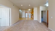 Located at 1551 Belsly Blvd in Moorhead, Minnesota, this single-floor unit offers a functional and well-organized layout designed for comfortable everyday living. The open-concept living area flows directly into the kitchen, creating a spacious, connected feel. The kitchen is equipped with warm honey-toned wooden cabinetry, ample counter space, and a full suite of white appliances including a refrigerator, electric range with over-the-range microwave, and dishwasher. Tile flooring in the kitchen provides easy maintenance, while plush carpet throughout the living and bedroom areas adds warmth underfoot. A dedicated laundry alcove with a full-size washer and dryer is conveniently accessible from the main living space. The bedrooms are generously sized, each featuring carpet flooring, natural light from windows with blinds, and baseboard heating. Closet options include both standard reach-in closets and a spacious walk-in closet with wire shelving for organized storage. The unit includes two bathrooms: one full bath with a stand-up shower, vanity, and tile flooring, and a second bathroom with tile flooring and baseboard heating. Textured ceilings and neutral warm-beige walls throughout create a cohesive, move-in-ready atmosphere.
