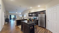 Located at 17 Hawthorne Gate in Dayton, Ohio, this single-floor home offers a well-designed, open layout that balances comfort and functionality. The kitchen serves as a focal point of the living space, featuring dark espresso cabinetry, granite countertops, stainless steel appliances, a center island with seating, and a peninsula bar — all illuminated by stylish pendant lighting. Vaulted ceilings in the kitchen and living areas enhance the sense of openness and airiness throughout.

Rich hardwood-style flooring flows through the main living areas, transitioning to plush carpet in the bedrooms. The living room is a welcoming retreat with vaulted ceilings and tasteful, neutral wall tones. A dedicated dining area benefits from a large sliding glass door that frames scenic outdoor views, filling the space with natural light.

The primary bedroom is generously proportioned, complete with a ceiling fan, multiple windows, and access to a spacious walk-in closet outfitted with wire shelving systems. Bathrooms are appointed with dark vanity cabinetry, granite-style countertops, hardwood-style flooring, and tub/shower combinations. Additional living areas provide flexible space for varied uses. The home's cohesive design, quality finishes, and thoughtful layout make it a distinctive residence in the Dayton area.