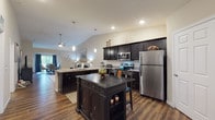 Located at 17 Hawthorne Gate in Dayton, Ohio, this single-floor home offers a well-designed, open layout that balances comfort and functionality. The kitchen serves as a focal point of the living space, featuring dark espresso cabinetry, granite countertops, stainless steel appliances, a center island with seating, and a peninsula bar — all illuminated by stylish pendant lighting. Vaulted ceilings in the kitchen and living areas enhance the sense of openness and airiness throughout.

Rich hardwood-style flooring flows through the main living areas, transitioning to plush carpet in the bedrooms. The living room is a welcoming retreat with vaulted ceilings and tasteful, neutral wall tones. A dedicated dining area benefits from a large sliding glass door that frames scenic outdoor views, filling the space with natural light.

The primary bedroom is generously proportioned, complete with a ceiling fan, multiple windows, and access to a spacious walk-in closet outfitted with wire shelving systems. Bathrooms are appointed with dark vanity cabinetry, granite-style countertops, hardwood-style flooring, and tub/shower combinations. Additional living areas provide flexible space for varied uses. The home's cohesive design, quality finishes, and thoughtful layout make it a distinctive residence in the Dayton area.