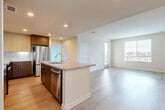 Located at 3461 La Cadena Dr in Riverside, CA, this well-appointed 2-bedroom, 2-bathroom residence offers a thoughtfully designed single-floor layout. The open-concept living, dining, and kitchen area serves as the heart of the home, bathed in natural light from large windows. The modern kitchen is a standout feature, showcasing two-tone cabinetry in rich walnut and crisp white, a subway tile backsplash, quartz countertops, a center island with a built-in sink, and a full suite of stainless steel appliances. Light wood-style flooring flows throughout the main living areas, creating a warm and cohesive aesthetic. The generously sized primary bedroom offers direct access to a private bathroom and a closet, while the secondary bedroom features plush carpeting and a bright window with outdoor views. Both bathrooms are finished with clean, white tiled tub-shower combinations and wood-look flooring. Additional conveniences include in-unit laundry, multiple closets for ample storage, and a private balcony. The overall ambiance is clean, bright, and contemporary, reflecting a modern residential design ideal for comfortable everyday living.