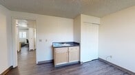 Located at 1555 NE Merman Dr in Pullman, Washington, this three-bedroom, one-bathroom unit offers a practical and well-organized single-floor layout. Wood-look flooring runs throughout the entire space, providing a cohesive and easy-to-maintain finish, while textured ceilings add a classic touch to each room.

The living room greets you at the entrance with a dark-paneled front door and a window that allows natural light to fill the open area. The kitchen is efficiently designed in a U-shaped configuration, featuring light maple cabinetry, a stainless steel dishwasher, a full-size refrigerator, and a window-facing sink. A stacked washer and dryer unit is conveniently integrated into the kitchen space.

Each bedroom is well-proportioned and features its own closet. The spacious primary bedroom stands out with a built-in vanity, sink with light maple cabinetry, a large mirror with Hollywood-style lighting, and a sliding closet. The additional bedrooms are bright, with windows and ample floor space suitable for a bed and a study area.

The shared bathroom is clean and functional, featuring a full soaking tub with white subway tile surround, a towel bar, and matching wood-look flooring. A connecting hallway ties all rooms together, making for an efficient and livable floor plan.