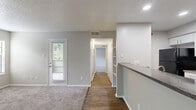 Located on Kelly Boulevard in Dallas, Texas, this single-story, one-bedroom, two-bathroom residence offers a functional and well-organized layout. The combined kitchen and living area serves as the heart of the home, where plush carpeting and neutral-toned walls create a warm, understated atmosphere. A white brick fireplace flanked by two windows anchors the living room, allowing natural light to fill the space. A door provides direct exterior access, adding convenience to everyday living. Built-in shelving near the kitchen transition adds practical storage and visual interest.

The galley-style kitchen features wood-look flooring, white cabinetry, dark granite-style countertops, and black appliances including a range, microwave, refrigerator, and dishwasher — a clean, functional setup for home cooking.

The spacious primary bedroom is carpeted for comfort, includes a ceiling fan with light fixture, and benefits from a window with green outdoor views. A dedicated closet provides organized storage. The hallways connect rooms efficiently, with wood-look flooring carrying throughout.

Both bathrooms are finished in white with tub-shower combinations and wood-look flooring, maintaining a clean and consistent aesthetic throughout the home.