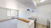 Located at 1191 High Ave in Oshkosh, Wisconsin, this 2-bedroom, 1-bathroom unit offers a practical and comfortable single-floor layout. The living room is the largest area of the home, featuring plush carpeted flooring, a large picture window that fills the space with natural light and provides views of the surrounding greenery, and baseboard heating along with a wall-mounted AC unit for year-round climate control. The clean, white walls throughout create a bright and neutral backdrop.

The primary bedroom is generously sized, outfitted with soft carpeting, a ceiling fan with integrated lighting, and a mirrored sliding-door closet that adds both storage and a sense of openness. The second bedroom also features carpeting, a ceiling fan, a window with natural light, and built-in wall shelving for added storage convenience. Both bedrooms are served by baseboard heating.

The bathroom includes wood-look vinyl flooring, a full tub and shower with neutral tile surround, and a vanity with storage. A connecting hallway links all rooms efficiently. The overall aesthetic is clean, simple, and functional, making this a well-organized unit well-suited for comfortable everyday living in a residential Oshkosh neighborhood.