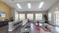 This single-floor community space is thoughtfully designed to serve as both a welcoming social hub and a functional leasing or management office. The architecture is defined by soaring vaulted ceilings that lend an airy, open feel throughout, complemented by neutral gray walls and rich dark hardwood-style flooring that flows seamlessly from room to room.

The main lounge area is generously sized, featuring a stylish seating arrangement with a gray sectional sofa, patterned accent chairs, and a vibrant pink geometric area rug. Multiple large windows dressed with white horizontal blinds fill the space with abundant natural light and offer views of the surrounding greenery. Elegant glass-top coffee tables and coordinated décor complete the inviting atmosphere.

Adjacent to the lounge, a reception area is anchored by a substantial dark wood desk, framed artwork, and direct sightlines to the entrance — ideal for staff-resident interaction. French doors with grid-pane glass panels connect different zones of the space, enhancing both openness and architectural character.

A dedicated dining nook features a round table with modern chairs set against a warm golden accent wall, alongside a beverage station with a mini-refrigerator and coffee maker. The kitchenette area is outfitted with granite countertops, dark cabinetry, a stainless steel sink, and ample counter space, providing practical amenity support for the overall facility.