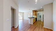 Located in the Porter Ranch neighborhood of Los Angeles, this 2-bedroom, 2-bathroom residence offers a well-designed single-floor layout that maximizes comfort and functionality. The open-concept kitchen and living area serves as the heart of the home, where warm hardwood-style flooring flows seamlessly throughout. The kitchen features a central island with a dark granite countertop, undermount double sink, pendant lighting, honey-toned wood cabinetry, and stainless steel appliances including a gas range, built-in microwave, dishwasher, and refrigerator. The living area extends naturally toward a sliding glass door that opens onto a private balcony with an arched architectural detail, filling the space with natural light and outdoor views. The generously sized primary bedroom includes direct balcony access and connects to a well-appointed en-suite bathroom featuring dark granite countertops, dual sinks, a large mirror, and a glass-enclosed shower and tub combination. A spacious walk-in closet with built-in shelving provides ample storage. The second bedroom is carpeted with natural light from dual windows. An in-unit laundry area with washer and dryer hookups adds everyday convenience, completing this thoughtfully laid-out home.