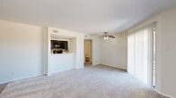 This single-floor, 2-bedroom, 2-bathroom residence offers a practical and comfortable layout designed for everyday living. The spacious living room features plush carpeting, a ceiling fan with light fixture, and a sliding glass door that fills the space with natural light while providing access to an outdoor area with open views. A pass-through opening connects the living room to the kitchen, which is finished with rich dark cabinetry, granite-style countertops, a mosaic tile backsplash, black appliances including a range, microwave, and refrigerator, and durable wood-look flooring. The primary bedroom is generously sized, equipped with a ceiling fan, and includes access to both a walk-in closet with dual shelving rods and an en-suite bathroom. The second bedroom also features carpeting, a ceiling fan, and a window with natural light. Both bathrooms are appointed with dark wood vanities, granite-style countertops, framed mirrors, and wood-look flooring. Three closets throughout the unit provide ample storage. A hallway connects the bedroom wing to the main living areas, completing a cohesive and functional floor plan suited for comfortable daily living.