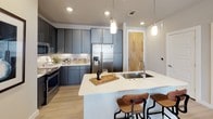 Located at 905 S Harwood St in Dallas, TX, this single-floor residence offers a contemporary design with thoughtfully appointed spaces throughout. The kitchen serves as a central highlight, featuring slate-gray cabinetry extending to the ceiling, a white quartz waterfall island with an undermount sink, stainless steel appliances including a French door refrigerator and range, and a classic subway tile backsplash. Pendant lighting and light wood-tone flooring complete the polished look.

The living area is bright and welcoming, with large windows that allow natural light to fill the space while framing views of the surrounding Dallas cityscape. A ceiling fan adds comfort, and the neutral color palette creates a versatile backdrop for any décor style.

Multiple bedrooms offer comfortable retreats, each with large windows, ceiling fans, and plush carpeting. The primary bedroom connects to a well-designed en-suite bathroom featuring dual sinks set in a dark-cabinetry vanity with quartz countertops, light wood flooring, and a walk-in closet with built-in shelving. A second bathroom mirrors the same refined aesthetic, with a single vanity and combination tub and shower. The overall ambiance throughout the residence is modern, clean, and well-lit, reflecting urban sophistication.