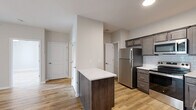 Located at Hurstbourne Pointe in Louisville, KY, this thoughtfully designed one-bedroom, two-bathroom residence offers a cohesive modern aesthetic across its single-floor layout. Warm hardwood-style flooring flows seamlessly throughout every room, creating a unified and inviting atmosphere.

The kitchen is a standout feature, equipped with a full suite of stainless steel appliances including a refrigerator, range, and over-the-range microwave. Rich, dark cabinetry with brushed hardware is complemented by white quartz countertops and a classic subway tile backsplash. A central island provides additional prep space and a natural divide between the kitchen and the open living area.

The spacious bedroom is filled with natural light from a window fitted with blinds and is topped with a ceiling fan for added comfort. It connects conveniently to the rest of the unit. The walk-in closet features wire shelving for ample storage. Two full bathrooms serve the unit, one featuring a tub-shower combination with brushed nickel fixtures.

A dedicated laundry room with hookups and built-in shelving adds practical functionality. The unit's neutral color palette of soft greige tones and white trim throughout lends a clean, move-in-ready appeal to this well-organized Louisville residence.