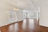 This single-story, 3-bedroom, 2-bathroom home offers a thoughtfully designed layout that balances comfort and functionality. The entrance leads into a hallway with warm hardwood flooring that extends throughout the main living areas, creating a cohesive and inviting atmosphere. The spacious living room features large windows that allow generous natural light to fill the space, with views of the surrounding exterior. An elegant chandelier anchors the adjacent dining area, which opens to the outdoors through a glass-paned door, adding to the airy feel of the common areas.

The kitchen is fitted with rich dark wood cabinetry, light quartz countertops, a double stainless steel sink, and a dishwasher, providing ample storage and a clean, practical workspace. Both bathrooms mirror this design aesthetic, featuring matching dark wood vanities with quartz counters, large mirrors, and tiled tub-shower combinations.

The bedrooms are carpeted for added comfort, each featuring ceiling fans with lighting. The primary bedroom offers a generous footprint with direct access to a closet. The additional bedrooms are well-sized with windows providing natural light. Textured ceilings are present throughout, and the overall neutral color palette makes this a versatile and move-in-ready home.
