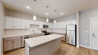 This well-appointed single-story home in Springfield, Missouri offers a clean, modern aesthetic throughout its two bedrooms and two bathrooms. The open-concept layout connects the living room and kitchen seamlessly, with light wood-look flooring flowing throughout the main living areas and recessed lighting adding a bright, airy feel. Ceiling fans in the living room and bedrooms enhance comfort year-round.

The kitchen is a standout feature, showcasing crisp white upper cabinetry paired with taupe lower cabinets, a classic subway tile backsplash, white quartz countertops, and a central island with pendant lighting overhead. Stainless steel appliances — including a refrigerator, electric range, microwave, and dishwasher — complete the space.

The primary bedroom is generously sized, featuring plush carpet, a ceiling fan, and direct access to a dedicated closet. The second bedroom is equally comfortable with carpet flooring, a ceiling fan, and a bright window. Both bathrooms are finished with quartz vanity tops and tile flooring, with one bathroom featuring a full tub-shower combination.

A dedicated laundry room houses a full-size front-loading washer and dryer with overhead shelving. The home's neutral gray palette, modern finishes, and functional layout make it a highly livable and attractive space.