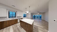 This well-appointed 2-bedroom, 3-bathroom residence at 1721 Motor Parkway in Hauppauge, NY offers a thoughtfully designed single-floor layout with a modern aesthetic throughout. The open-concept kitchen and living area serves as the heart of the home, highlighted by a large center island with a quartz countertop, two-tone cabinetry featuring rich walnut lower cabinets and crisp white uppers, a subway tile backsplash, and stainless steel appliances. Pendant lighting over the island and a ceiling fan in the living area add both style and functionality, while sliding glass doors open to a balcony offering expansive outdoor views. Light wood-look flooring flows throughout the main living areas, complementing the neutral, contemporary color palette. The hallways are clean and bright, with recessed lighting and easy access to a well-designed bathroom featuring a pedestal sink and marble-style tile flooring. The bedrooms are generously proportioned, with soft carpeting and ceiling fans. The spacious primary bedroom includes access to a walk-in closet outfitted with built-in shelving and dual hanging rods. Three full bathrooms provide ample convenience. A dedicated in-unit laundry room with a full-size washer and dryer completes this functional and stylish residence.
