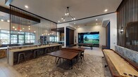 This single-story clubhouse in Humble, Texas, is a well-appointed community gathering space designed with a contemporary aesthetic and a broad range of amenities. The layout is divided into distinct yet interconnected zones, each thoughtfully designed for comfort and entertainment.

The game room serves as a central hub, featuring patterned tile flooring, a pool table, a shuffleboard table, and a ping-pong table. Vertical wood slat partitions define the space without fully enclosing it, maintaining an open, social atmosphere. A dedicated golf simulator room adjoins this area, enclosed with dark curtains and equipped with a large projection screen and turf mat, offering an immersive experience.

The catering kitchen is finished with light hardwood flooring, dark cabinetry, a stone-topped island, and a decorative hexagonal tile backsplash. Brass pendant lights add warmth overhead, while a wall-mounted TV and built-in sink provide functional convenience.

The lounge and dining areas feature soaring ceilings, floor-to-ceiling windows that invite natural light and outdoor views, and curated blue-toned artwork. Furnishings include tufted velvet dining chairs, a large communal table, and plush leather seating arranged around herringbone-patterned carpet. Sculptural chandeliers provide distinctive focal points throughout.