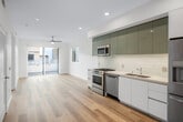Located at 2299 Harbor Blvd in Costa Mesa, California, this single-floor unit showcases a clean, modern design characterized by light wood-tone flooring, crisp white walls, and recessed lighting throughout. The open-concept layout creates a seamless flow between the kitchen and living areas, maximizing the sense of space.

The kitchen is a standout feature, equipped with a full suite of stainless steel appliances including a gas range, dishwasher, microwave, and refrigerator. Sleek, glossy teal upper cabinetry is paired with white lower cabinets, complemented by a light granite countertop and a white subway tile backsplash for a polished, contemporary look.

The living area opens directly to an outdoor space via sliding glass doors, inviting natural light and providing easy indoor-outdoor access. A ceiling fan enhances comfort in this bright, airy room. Additional rooms feature large sliding windows and modern flush-mount or ceiling fan lighting fixtures.

The bathroom is elegantly appointed with large-format marble-effect tile surrounding a soaking tub and glass-enclosed shower. A wood-toned vanity with a white countertop and an illuminated mirror complete the refined aesthetic. In-unit laundry is also present, adding everyday convenience to this thoughtfully designed space.