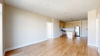 Located in the heart of Stamford, CT, this well-appointed 2-bedroom, 2-bathroom residence offers a thoughtfully designed single-floor layout with modern finishes throughout. The open-plan kitchen and living area serves as the central hub of the home, featuring light wood-toned cabinetry, white subway tile backsplash, stainless steel appliances including a gas range, built-in microwave, and refrigerator, along with a central island with a clean white countertop and stylish pendant lighting. Light hardwood flooring flows seamlessly through the living area, which is bathed in natural light from large sliding glass doors that open to a balcony with urban views of the Stamford skyline. Both bedrooms are generously sized, finished with plush wall-to-wall carpeting, and feature large windows that frame city and treetop views. The primary bedroom is notably spacious and benefits from dual windows, including a wide clerestory window maximizing light. The two bathrooms are well-finished: one features a sleek walk-in glass shower with grab bars and wood-look tile flooring, while the second offers a full soaking tub and shower combination with a contemporary vanity and illuminated mirror. The neutral color palette and clean lines throughout lend the space a calm, modern ambiance.