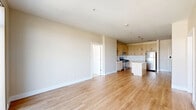 Located in the heart of Stamford, CT, this well-appointed 2-bedroom, 2-bathroom residence offers a thoughtfully designed single-floor layout with modern finishes throughout. The open-plan kitchen and living area serves as the central hub of the home, featuring light wood-toned cabinetry, white subway tile backsplash, stainless steel appliances including a gas range, built-in microwave, and refrigerator, along with a central island with a clean white countertop and stylish pendant lighting. Light hardwood flooring flows seamlessly through the living area, which is bathed in natural light from large sliding glass doors that open to a balcony with urban views of the Stamford skyline. Both bedrooms are generously sized, finished with plush wall-to-wall carpeting, and feature large windows that frame city and treetop views. The primary bedroom is notably spacious and benefits from dual windows, including a wide clerestory window maximizing light. The two bathrooms are well-finished: one features a sleek walk-in glass shower with grab bars and wood-look tile flooring, while the second offers a full soaking tub and shower combination with a contemporary vanity and illuminated mirror. The neutral color palette and clean lines throughout lend the space a calm, modern ambiance.