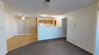 Located at 3901 NE Montgomery Blvd in Albuquerque, New Mexico, this single-floor unit offers a practical and comfortable layout designed for everyday living. The living area is carpeted and anchored by a fireplace with a sleek black mantle, creating a cozy focal point. Vertical blinds frame a sliding glass door that provides access to the outdoors, allowing natural light to filter into the space. A ceiling fan adds to the comfort of the adjoining room, which features light wood-look flooring for a clean, warm aesthetic. The kitchen is positioned behind a half-wall pass-through counter, offering an open connection to the living areas while maintaining a defined cooking space. It is equipped with wood-toned cabinetry, a white refrigerator, and an electric range. Light wood flooring continues throughout the kitchen, complementing the cabinetry tones. The bathroom includes a full tub and shower combination finished with classic white square tile and chrome fixtures. The bedroom features plush carpeting, mirrored sliding closet doors, and a sliding glass door with vertical blinds that brings in natural light. A textured ceiling is consistent throughout the unit. Overall, the space offers a straightforward, well-maintained layout suited for comfortable single-floor living.